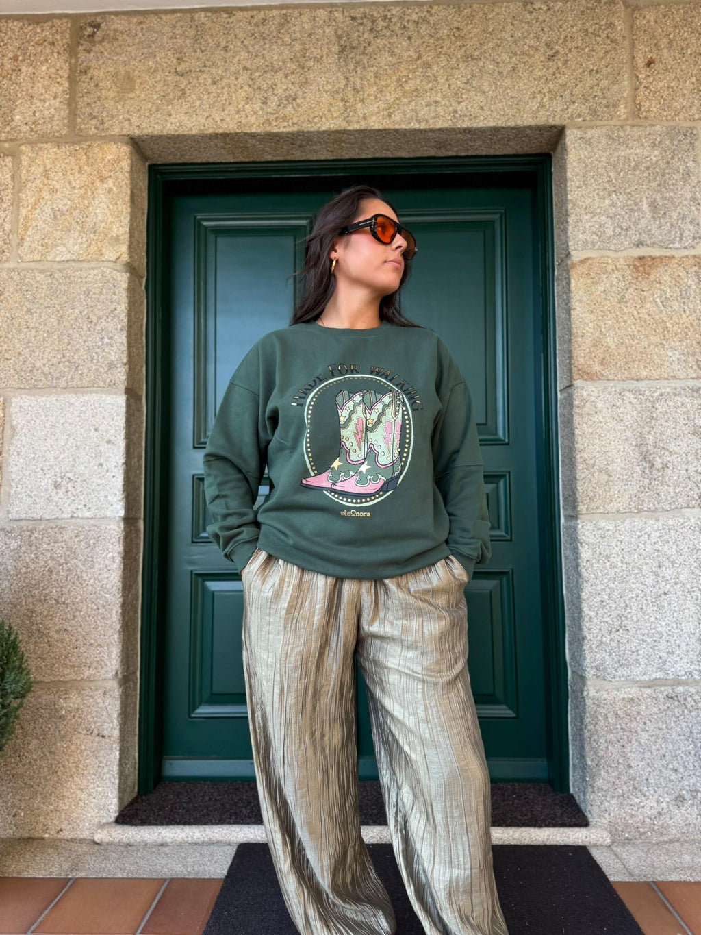 Mujer con sudadera verde eleOnora con estampado 'Made for Walking' de un par de botas camperas rosas y verdes