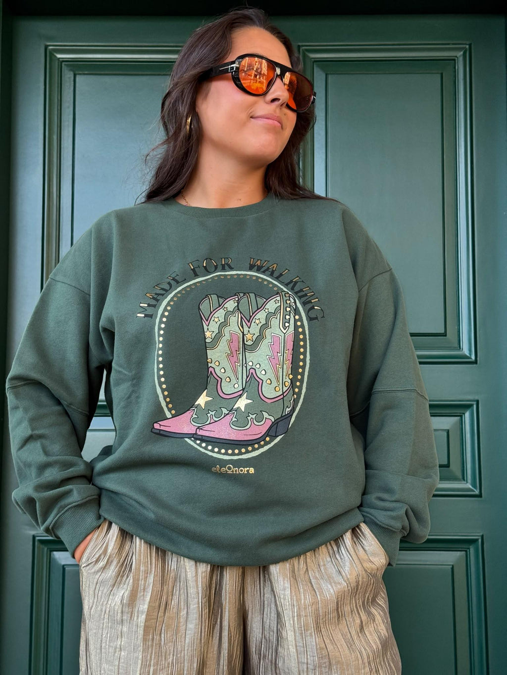 Primer plano del estampado de botas camperas 'Made for Walking' en sudadera verde eleOnora