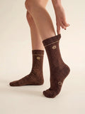 Par de calcetines chocolate con hilo lurex eleOnora puestos, mostrando el brillo del tejido en las piernas