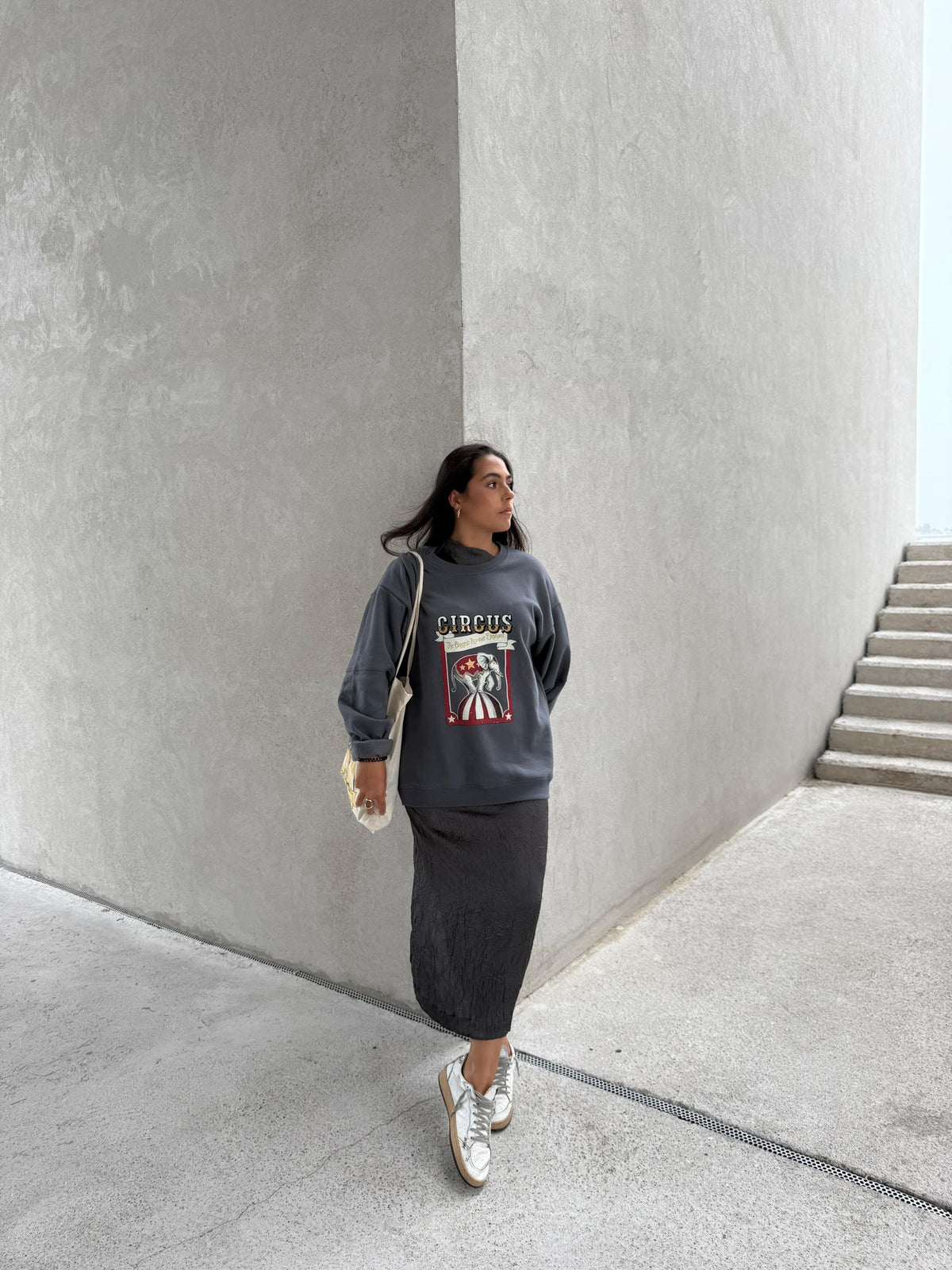 Mujer con sudadera gris azulado eleOnora de elefante de circo, combinada con falda negra