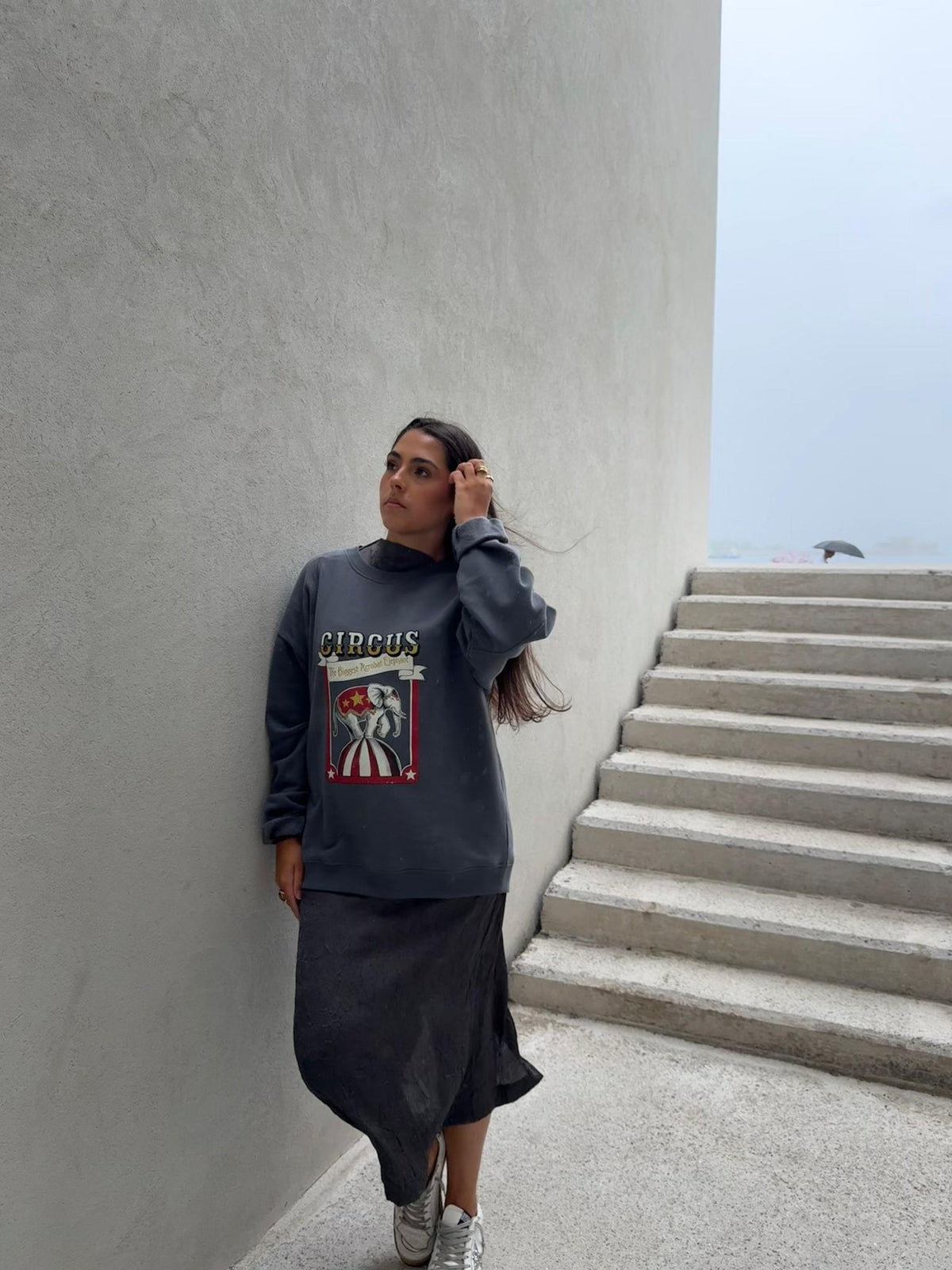 Mujer con sudadera gris azulado eleOnora de elefante de circo, con el pelo suelto